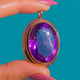 Antique 9ct Gold Amethyst Pendant, oval Amethyst and twisted Gold border on blue background