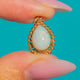 Pear-shaped Opal pendant with colourful flashes and a looped Gold border